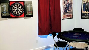 A room with a dartboard, framed playing cards, a poster, and a poker table. - 3BR●Private Bath Sweets●Game Room●Casino Nearby (Durant)