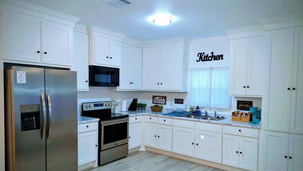 A kitchen with white cabinets, stainless steel appliances, a microwave, a stove, and a sink. - 3BR●Private Bath Sweets●Game Room●Casino Nearby (Durant)