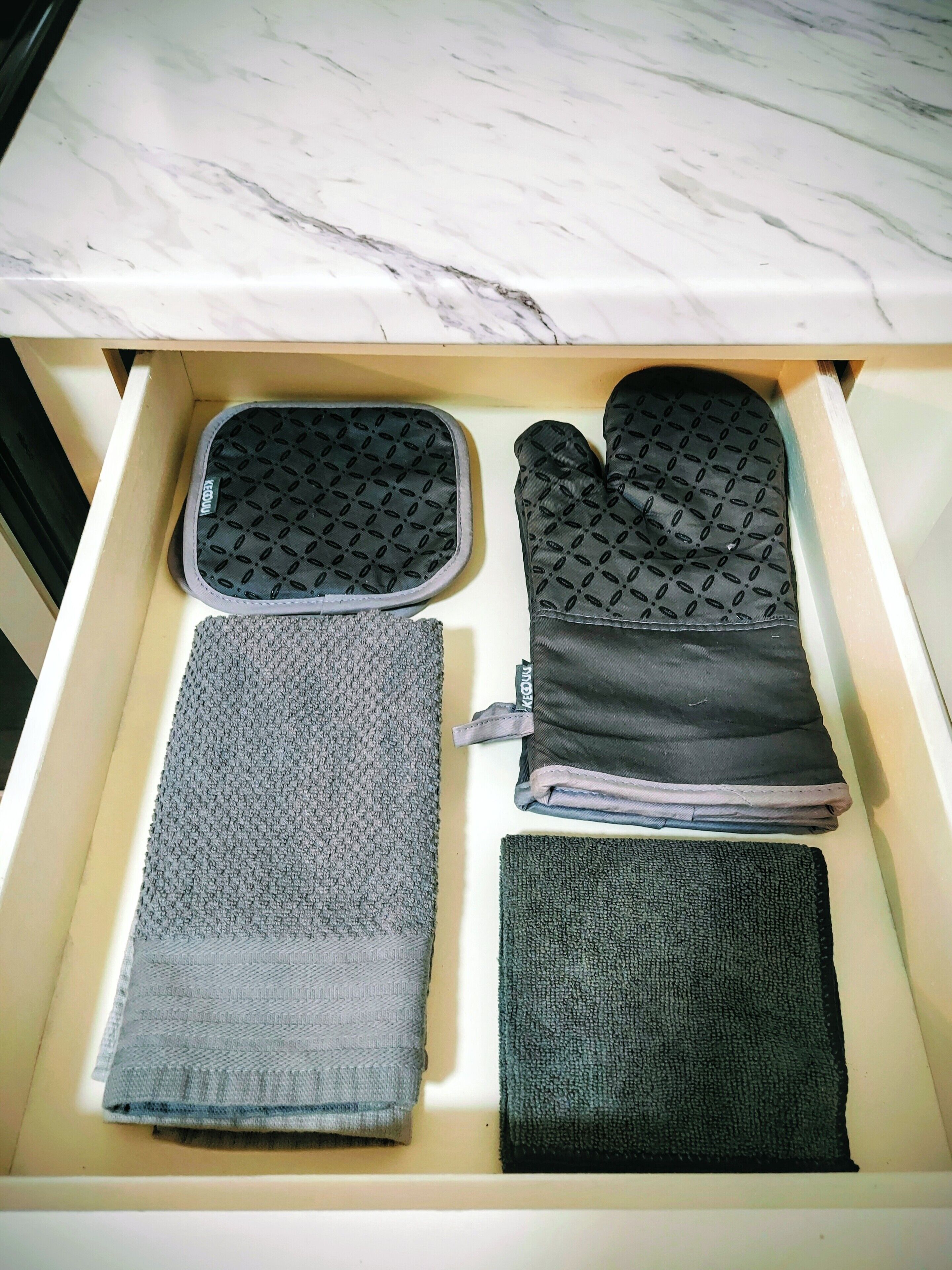 Een lade met keukengerei en een opgevouwen handdoek.