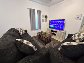 Una sala de estar con dos sofás, una mesa de centro, un televisor de pantalla plana y un mueble bajo.