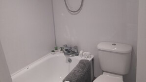 Un baño con bañera, inodoro y cabezal de ducha.