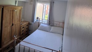 Un dormitorio con cama, un armario de madera y ventana con cortinas.