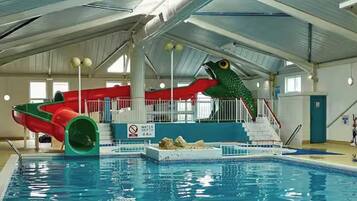 An indoor swimming pool with a water slide and a large fish sculpture.
