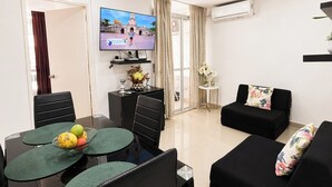 Een moderne woonkamer met een eethoek, een flatscreen televisie en een bank.