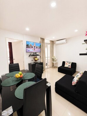 A modern living room with a dining area, a flat-screen TV, and a sofa. - Condominium in Cartagena (Cartagena de Indias)