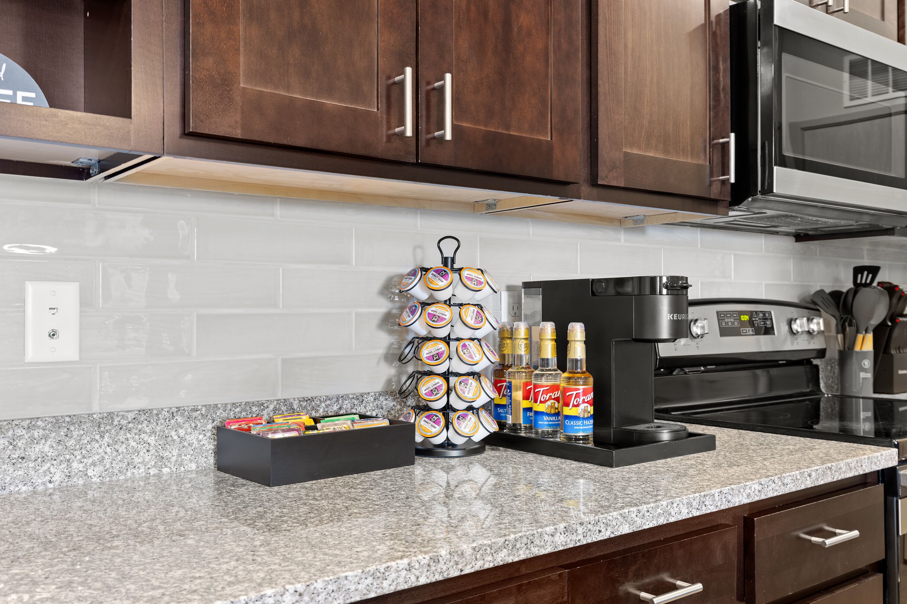 A kitchen with granite countertops, a coffee maker, and a microwave.