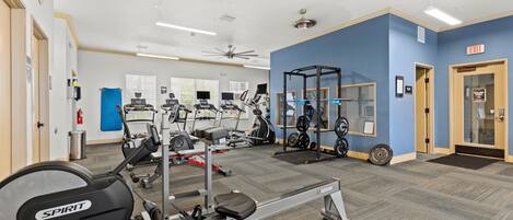 Un gimnasio con máquinas de cardio, equipo de levantamiento de pesas y una pared azul.
