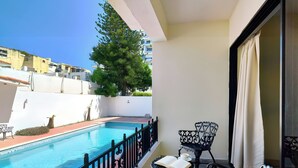 A balcony with a pool, outdoor furniture, and a view of buildings. - Roy Arias Suites (Santo Domingo)