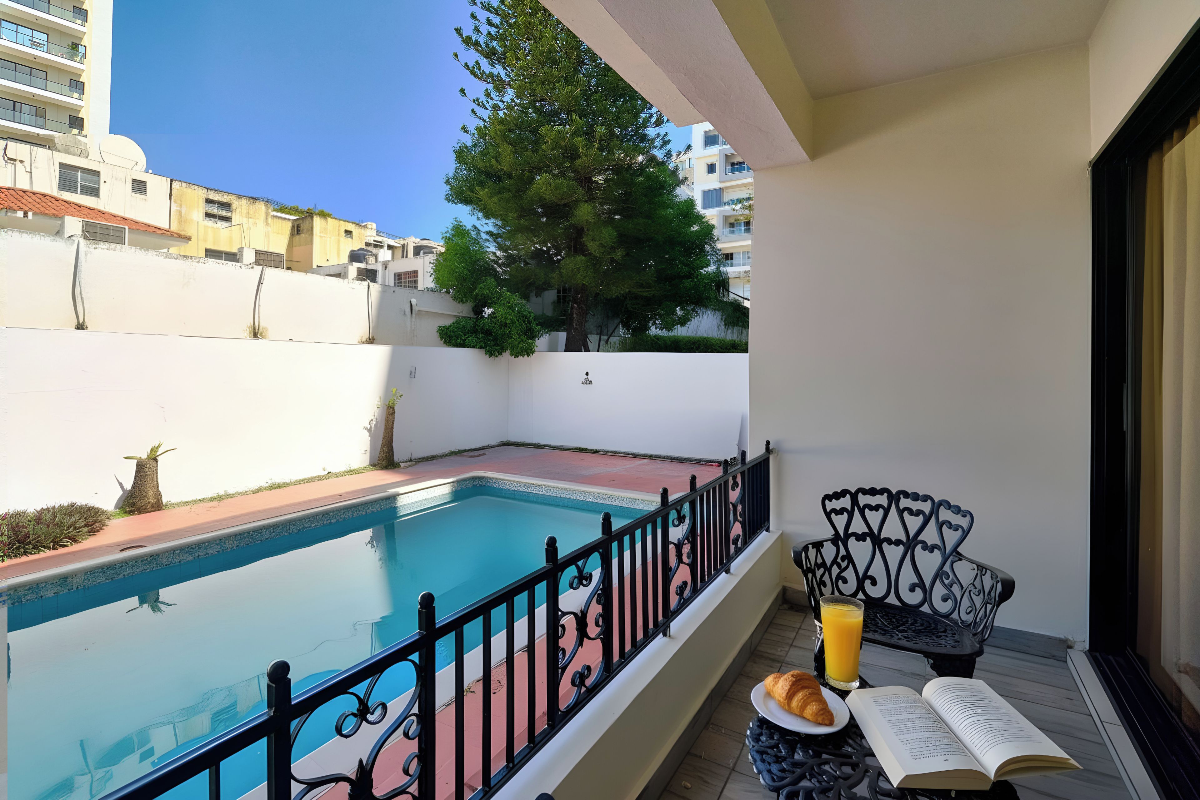 A balcony with a swimming pool, a book, and a glass of juice.