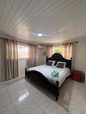 A bedroom with a bed, curtains, a window, and a tiled floor. - Dushi Aruba 3BDR-Villa - Private Pool •-Central Location - (Piedra Plat)