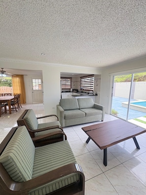 A living room with a sofa, a coffee table, and a dining area with a table and chairs. - Dushi Aruba 3BDR-Villa - Private Pool •-Central Location - (Piedra Plat)