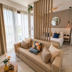 Ein modernes Hotelzimmer mit einer Couch, einem Bett mit Kissen, einem Spiegel, einer Holzvertäfelung und einem kleinen Tisch mit einer Vase.