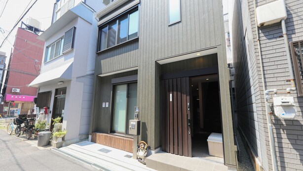 A modern building with a two-story entrance, a bicycle parked outside, and a small statue on the steps. - ODA VILLA@Namba (Osaka City)