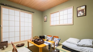 A traditional Japanese room with tatami flooring, a low wooden table, a sofa, and sliding doors. - ODA VILLA@Namba (Osaka City)
