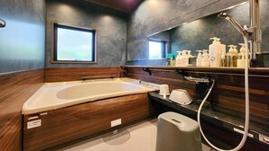 A modern bathroom with a large bathtub, a shower, and a vanity with toiletries. - taipi house  (Sado)