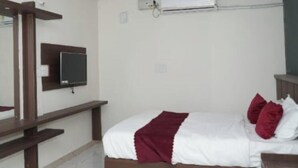 Un dormitorio con cama, televisor montado en la pared, aire acondicionado y ventilador de techo.