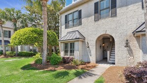 A two-story building with a stone facade, a covered entryway, and a visible staircase leading to the entrance. - Coastal Retreat on Beachview | Walk to Beach, Village + Family-Friendly Stay (Saint Simons Island)