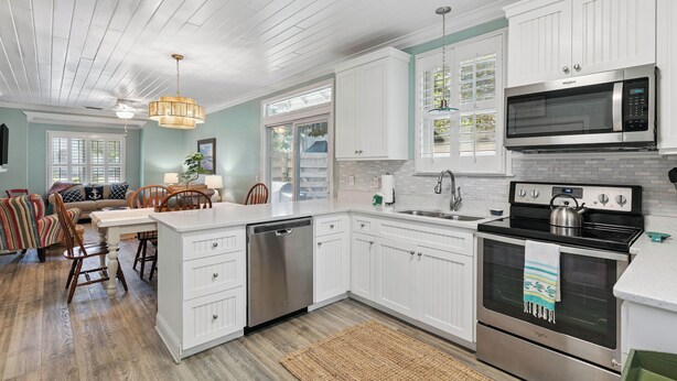 A kitchen with white cabinets, a stainless steel dishwasher, a microwave, and an oven. - Coastal Retreat on Beachview | Walk to Beach, Village + Family-Friendly Stay (Saint Simons Island)