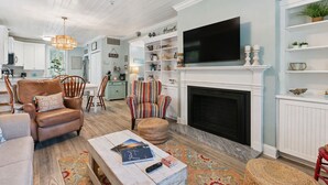 A living room with a fireplace, television, and various decorative items. - Coastal Retreat on Beachview | Walk to Beach, Village + Family-Friendly Stay (Saint Simons Island)