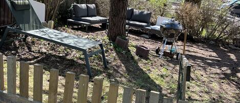 A wooden fence, a metal grill, and outdoor furniture in a backyard setting.