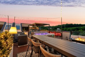 Eine Dachterrasse mit Whirlpool, Lichterketten und einem Neonzeichen.