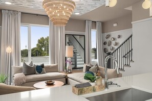 Ein modernes Wohnzimmer mit einer Couch, einem Couchtisch und einer Küchenzeile mit Spüle und Wasserhahn.