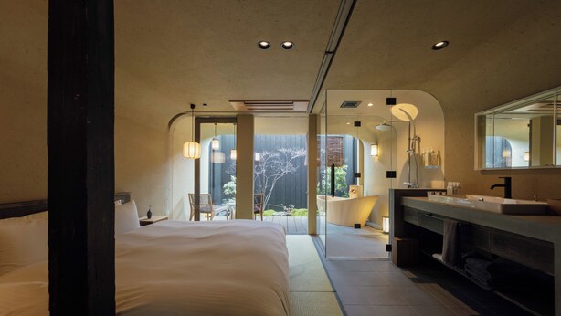 Une chambre d’hôtel moderne dotée d’un grand lit, d’une salle de bain avec un grand miroir et offrant une vue sur l’extérieur.