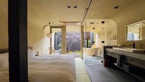 Une chambre d’hôtel moderne dotée d’un grand lit, d’une salle de bain avec un meuble-lavabo et offrant une vue sur l’extérieur.