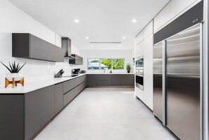 Eine moderne Küche mit einem großen, Edelstahl-Kühlschrank, grauen Schränken und einer weißen Arbeitsplatte.