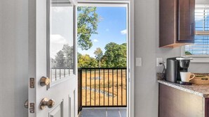A modern kitchen with a coffee maker, a white mug, and a view of a fenced outdoor area. - 19th Hole Haven in Sango 1625 Golf Club, #601 (Clarksville)