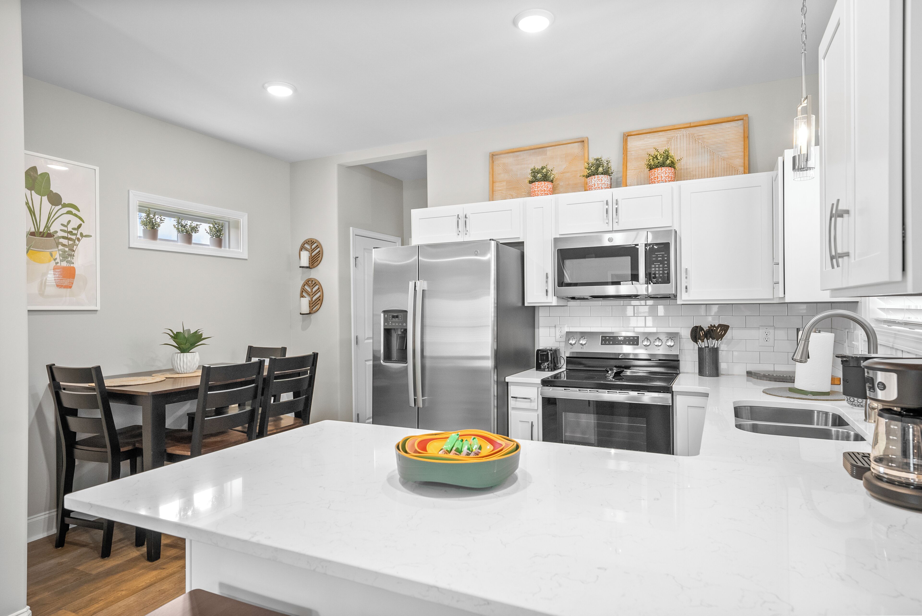 A modern kitchen with white cabinetry, stainless steel appliances, and a central island.