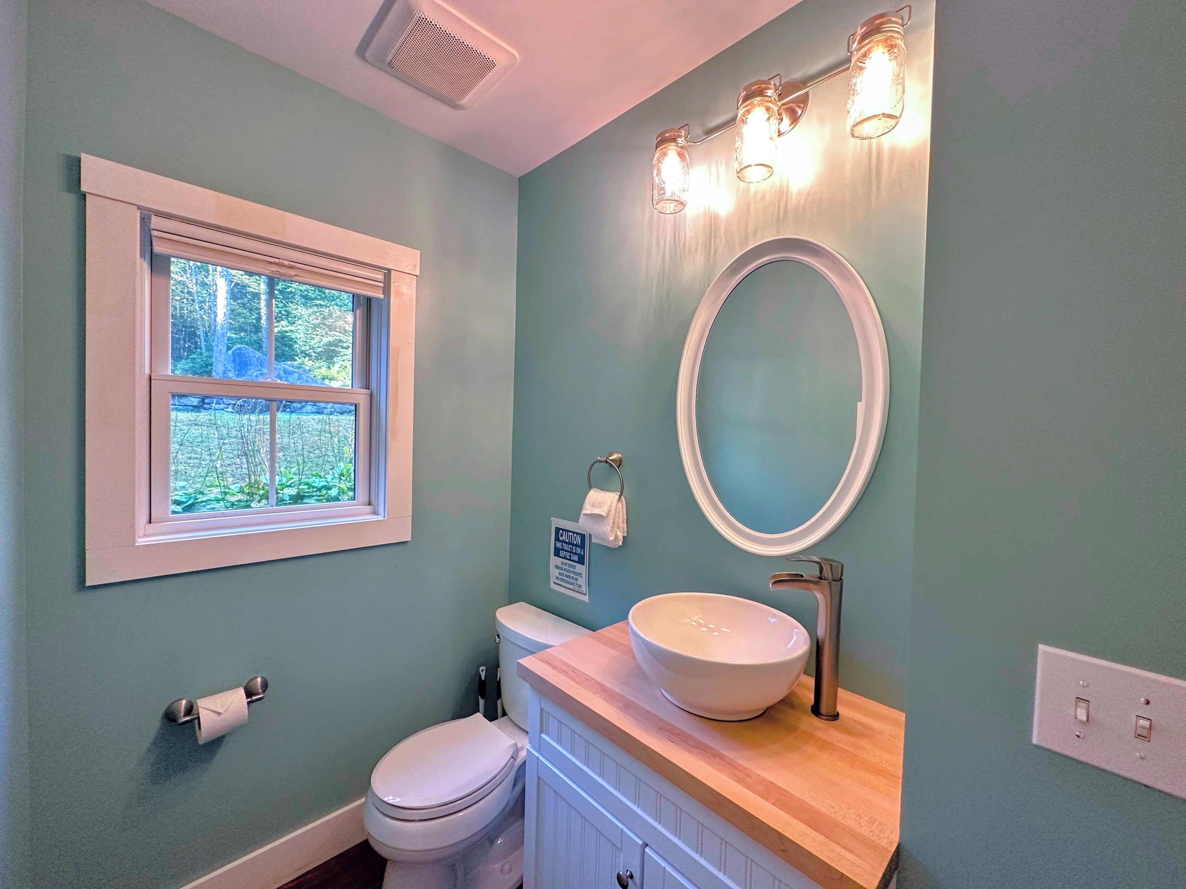 A bathroom with a toilet, sink, and window.
