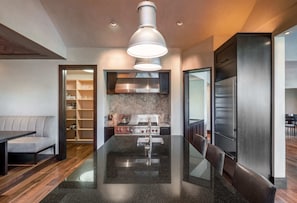 A modern kitchen with a central island, stainless steel appliances, and a dining area with a sofa and table.