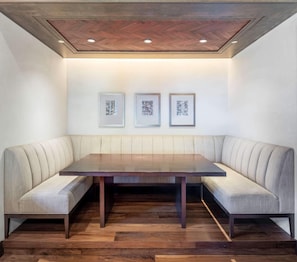 A modern dining area with a wooden table and upholstered bench seating.