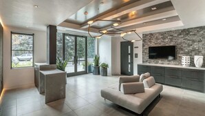 A modern living room with a sofa, a TV, and a stone wall.
