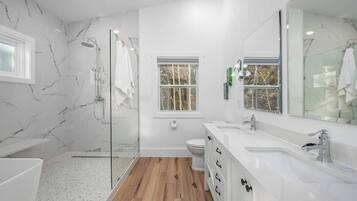 A modern bathroom with a glass shower enclosure, a white sink, and a large mirror.