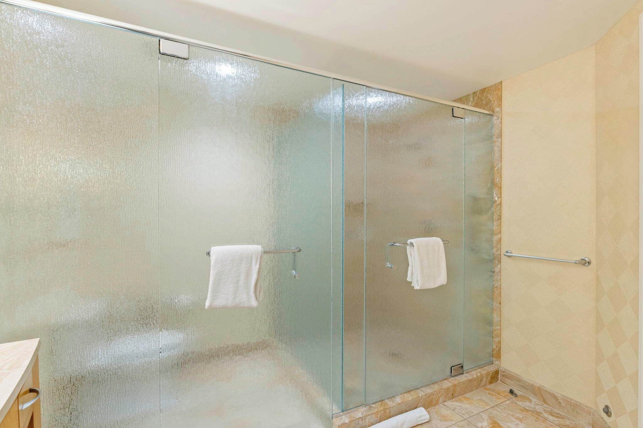 A glass-enclosed shower with a tiled floor, a towel rack, and a visible shower control panel.