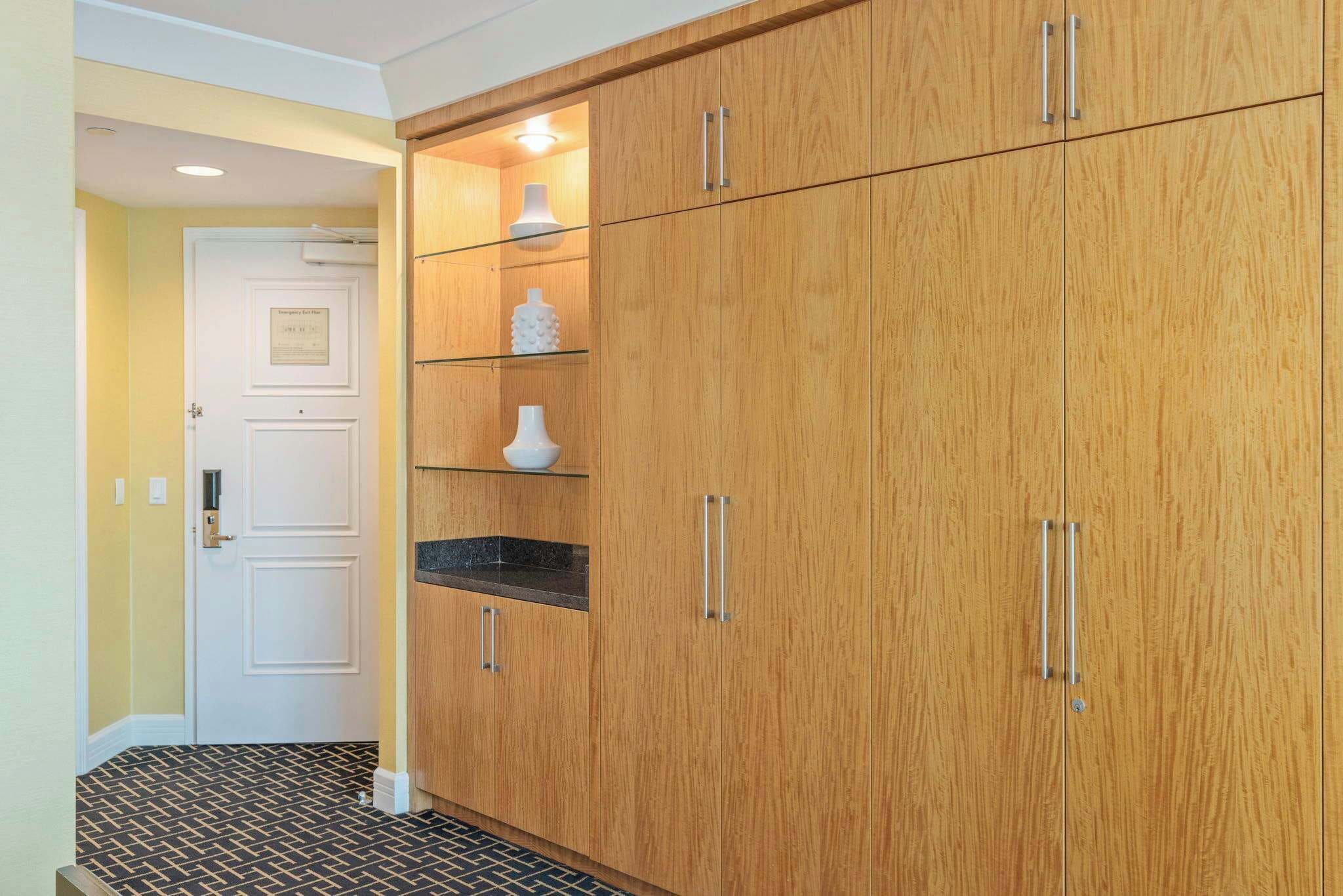 A hallway with a wooden wardrobe, a white door, and a patterned floor.