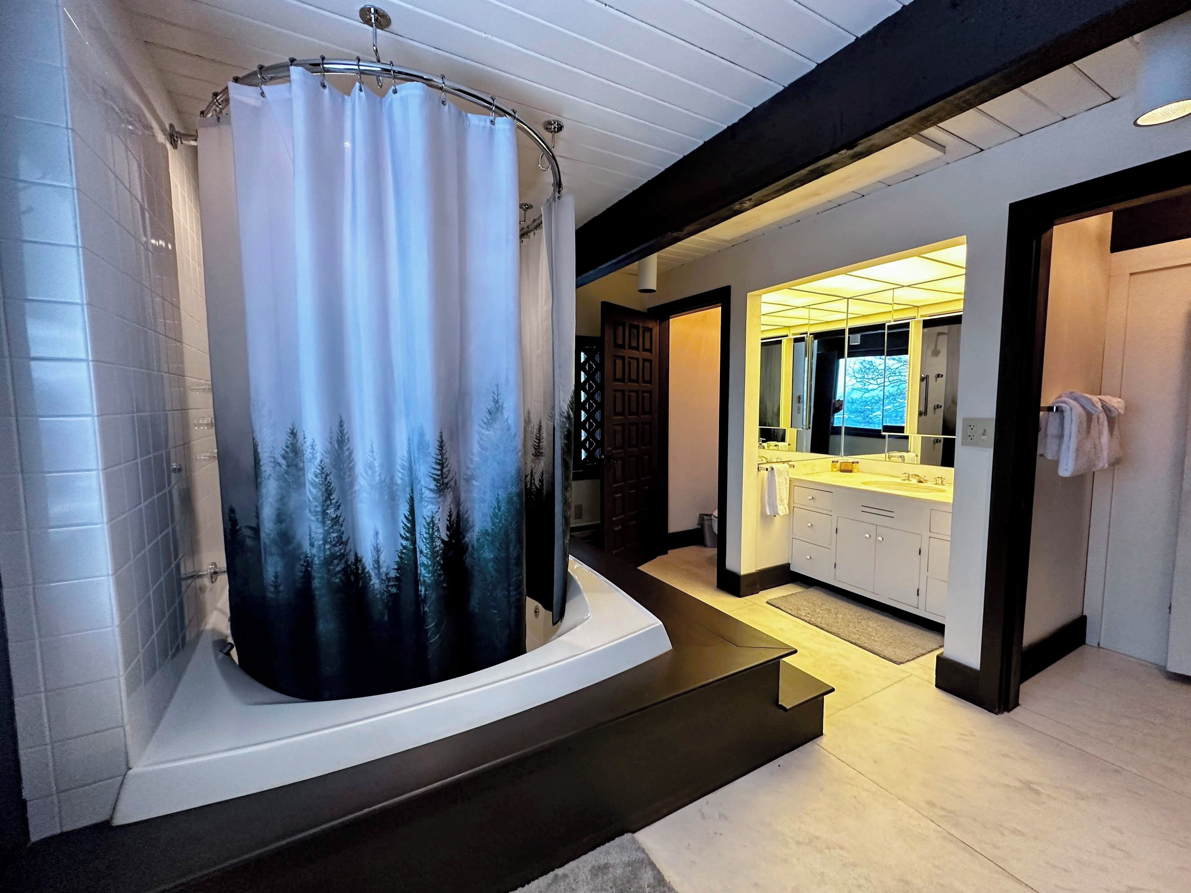 A modern bathroom with a large shower, a vanity with a mirror, and a bathtub.