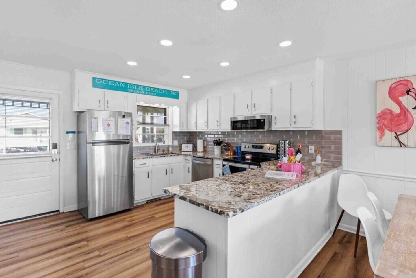 A modern kitchen with white cabinets, stainless steel appliances, and a granite countertop.