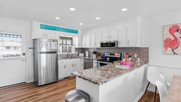 A modern kitchen with white cabinets, stainless steel appliances, and a granite countertop.