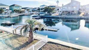 A marina with boats, a white fence, and a palm tree. - Pug Life - Walk to the Ocean! (Ocean Isle Beach)