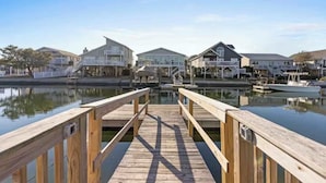 A wooden pier leading to a marina with houses on the other side. - Pug Life - Walk to the Ocean! (Ocean Isle Beach)
