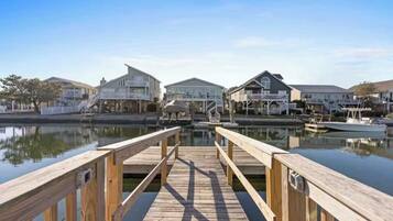 A wooden pier leading to a marina with houses on the other side.
