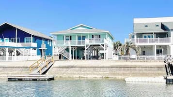 A beachfront property with a dock, a covered porch, and a staircase leading to the entrance.
