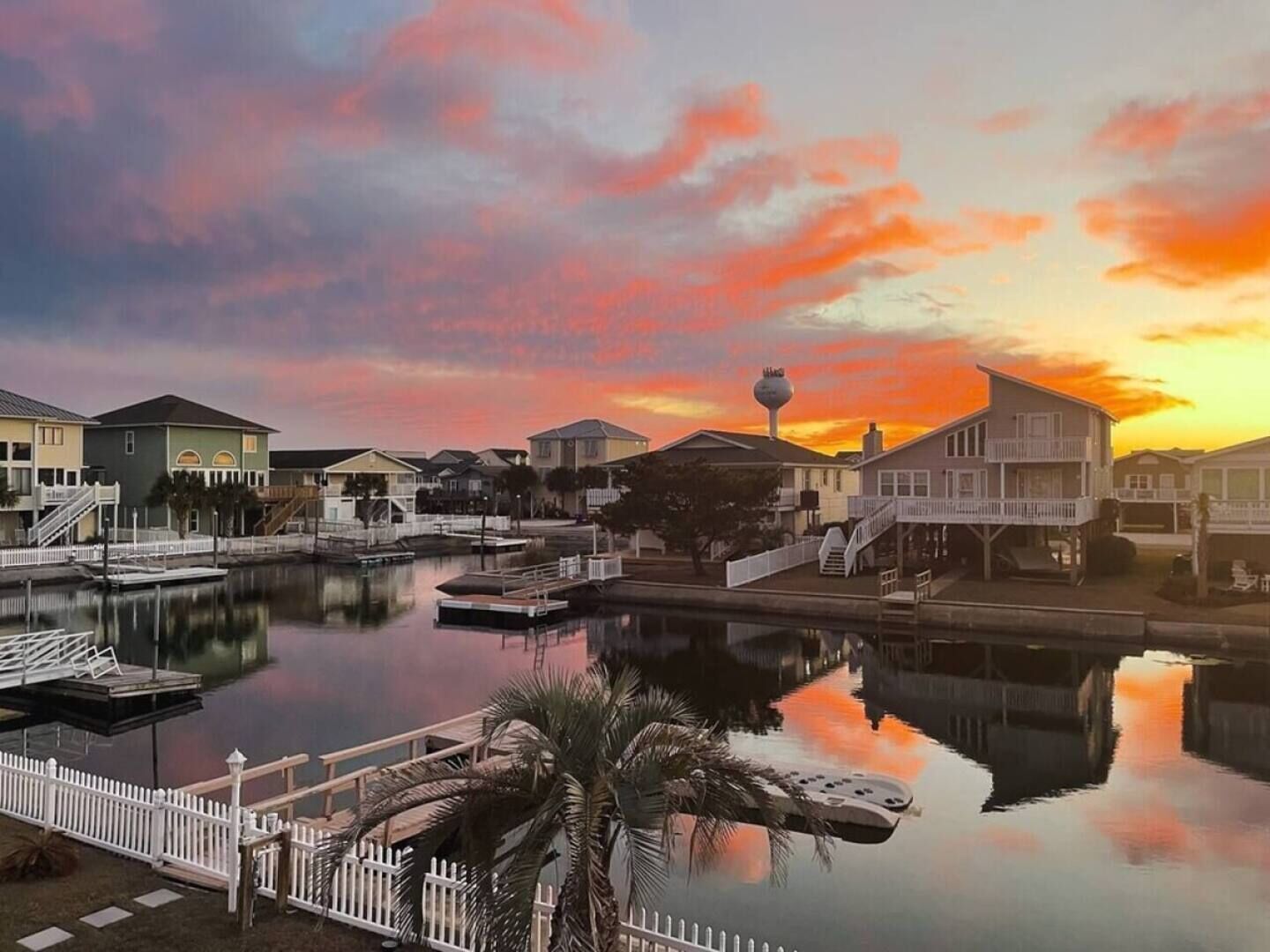 A waterfront property with a dock, a small boat, and a clear view of the sunset.