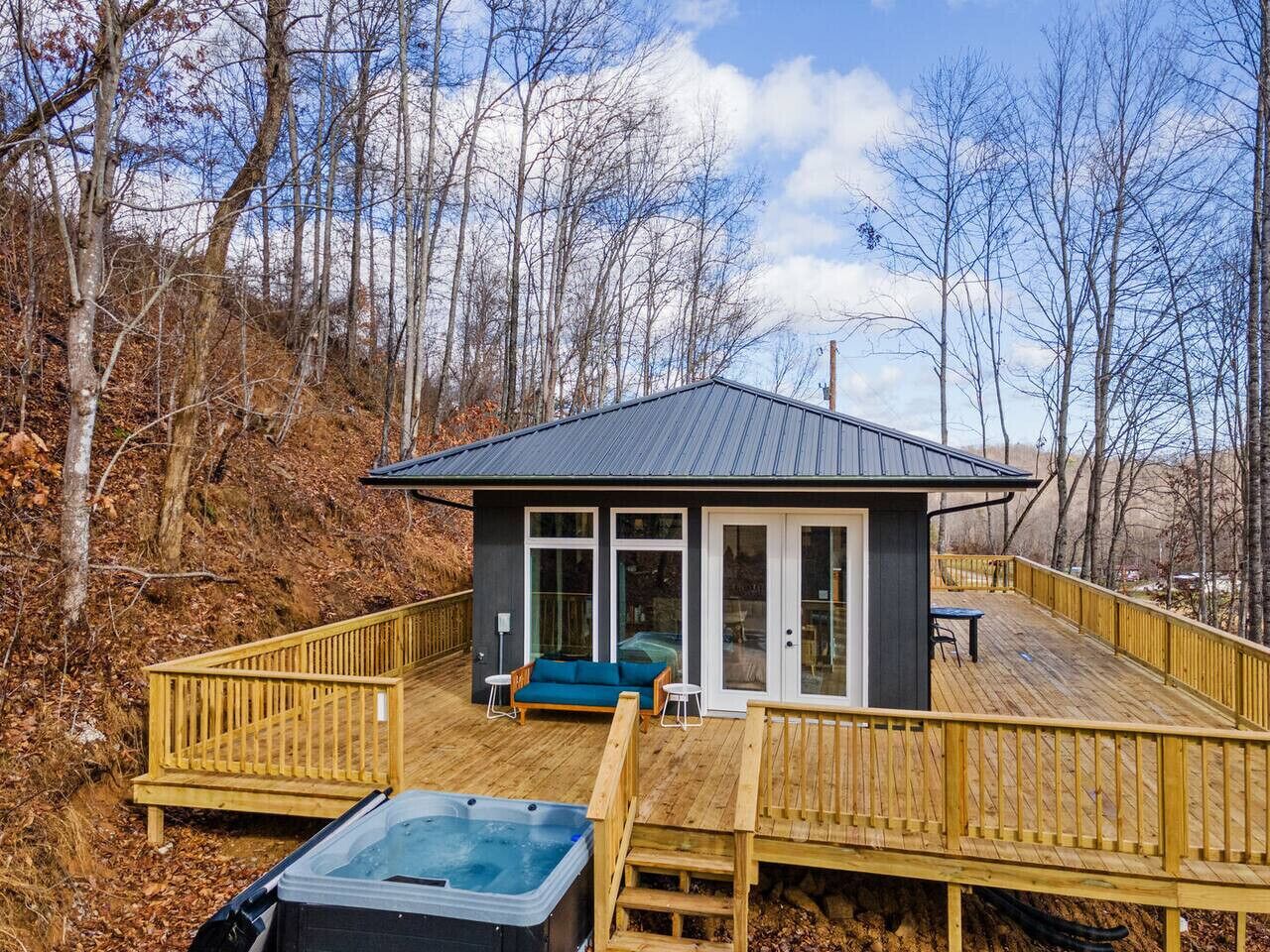 A cabin with a deck, a hot tub, and a sofa.