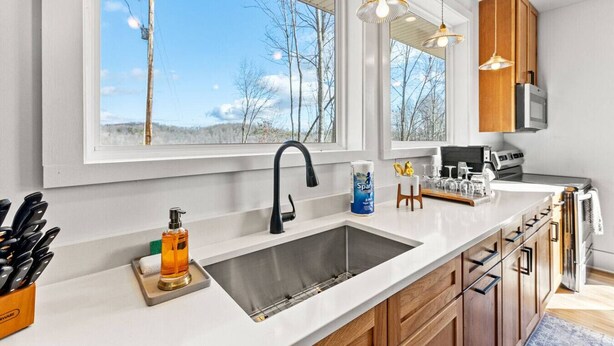 A modern kitchen with a large window, a stainless steel sink, wooden cabinets, and pendant lighting. - Primrose - Cave Run Lake OR Red River Gorge KY (Wellington)