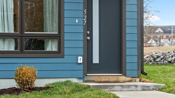 A house with a dark blue exterior, a gray door with a white number '527', and a small bush in front. - Unit #C 527 N 1st St (Clarksville)