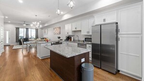 A modern kitchen with white cabinets, a granite countertop island, stainless steel appliances, and a dining area with a table and chairs. - Unit #C 527 N 1st St (Clarksville)